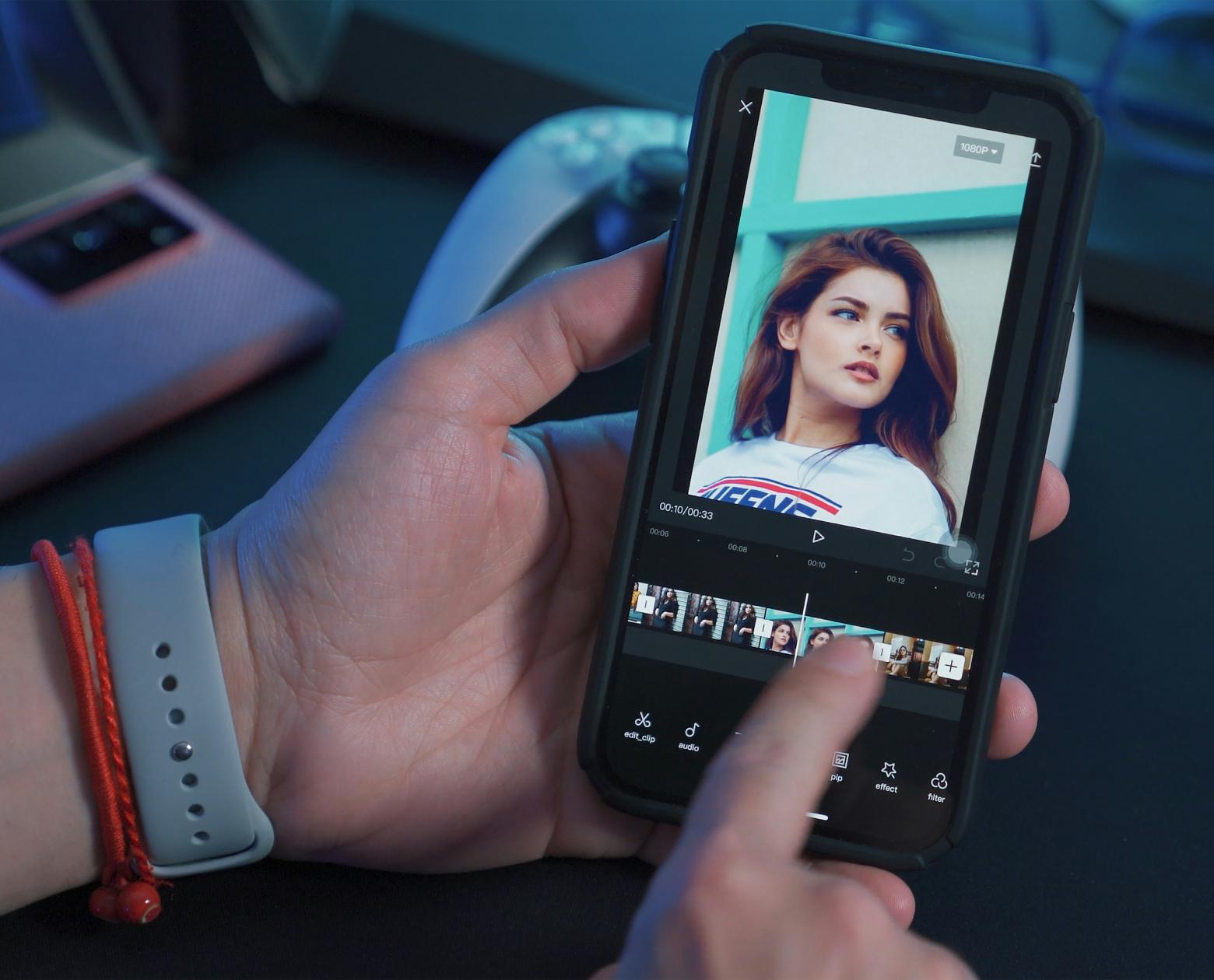 Hands editing a video timeline on a phone held over a desk